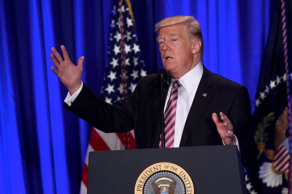 Donald Trump standing on a stage in front of a curtain