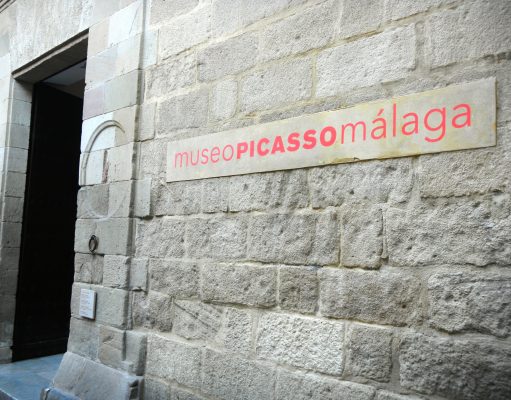 Spain Trivia: Malaga Travel Facts: Museo Picasso art, Botanic Gardens, city beaches & Semana Santa A stone building that has a sign on a brick wall